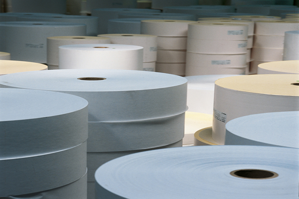 Rolls of paper in various sizes and colours, stacked in a storage room.