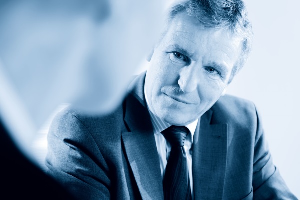 A man in a suit looks attentively and thoughtfully at his conversation partner.